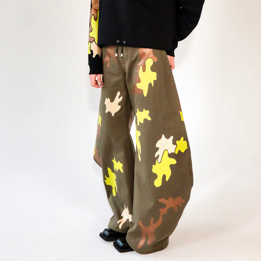 Person wearing camouflage-patterned barrel leg pants with a cropped hoodie with matching print on a white background