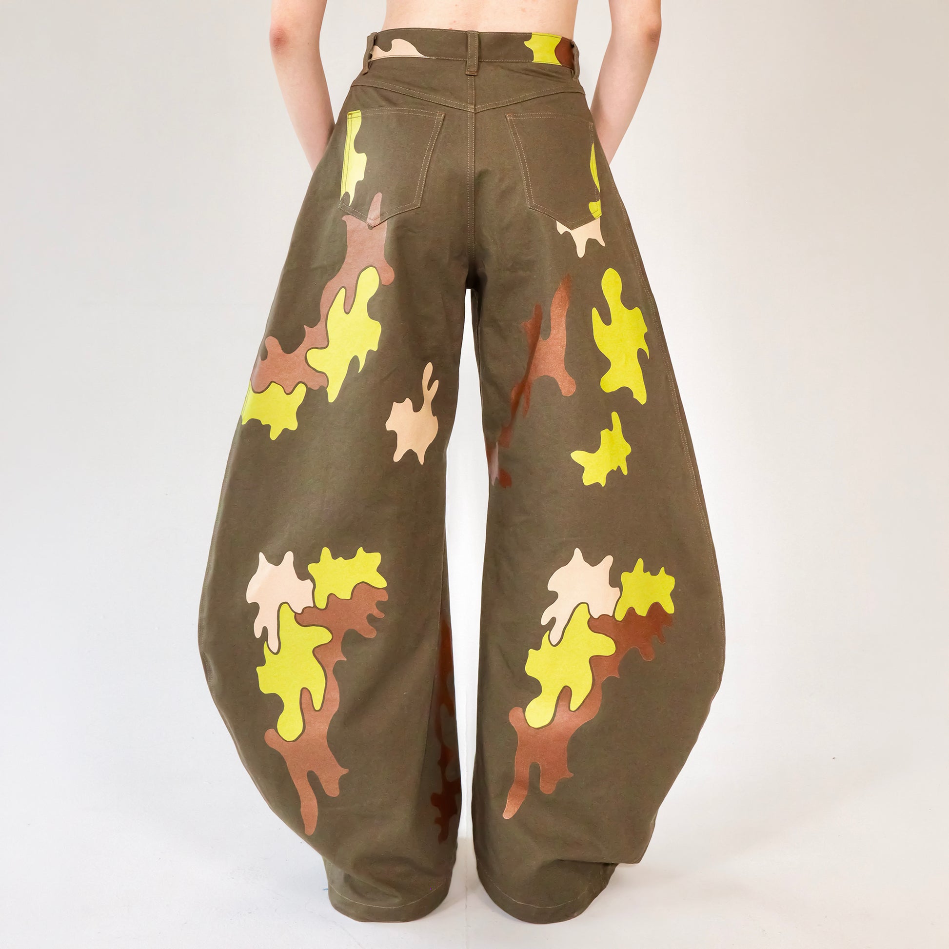 Person wearing camouflage-patterned barrel leg pants on a white background