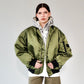 Person wearing a green bomber jacket with white printed hoodie underneath on a white backgorund