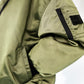 Close-up of a green jacket with MUCINA studio brand label on a white background
