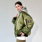 Person wearing a green bomber jacket with white printed hoodie underneath on a white background 