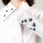 White stripped shirt with black ant hand embroidered designs on a plain background