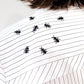 White stripped shirt with black ant hand embroidered designs on a plain background