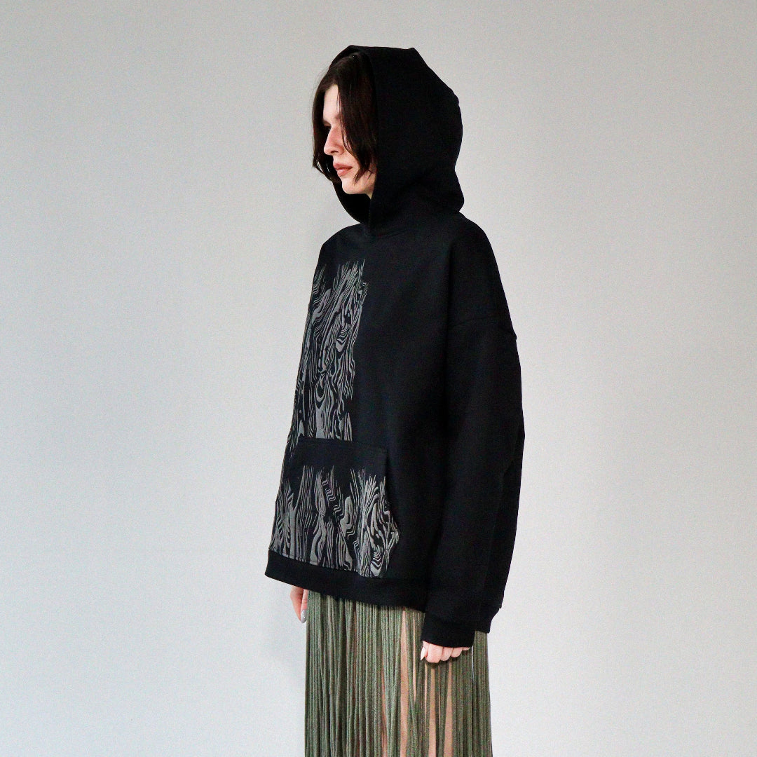 person wearing a limited quantity black french terry heavyweight hoodie with screen print graphic on front. hoodie made in riga, latvia