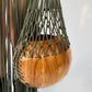 Wooden circular bag with a macrame handle next to a macrame skirt on a white background