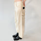 Beige barrel-leg cargo pants with patch detailing worn with a beige bomber jacket on a white background