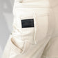 close up of Beige barrel-leg cargo pants with patch detailing with leather embossed logo label