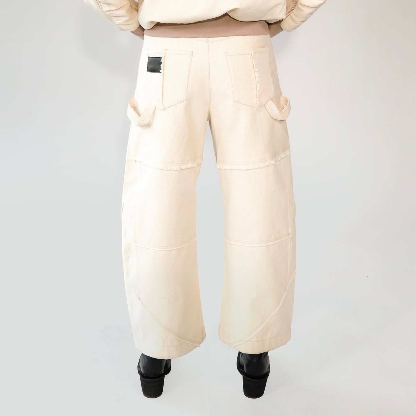 Beige barrel-leg cargo pants with patch detailing worn with a beige bomber jacket on a white background