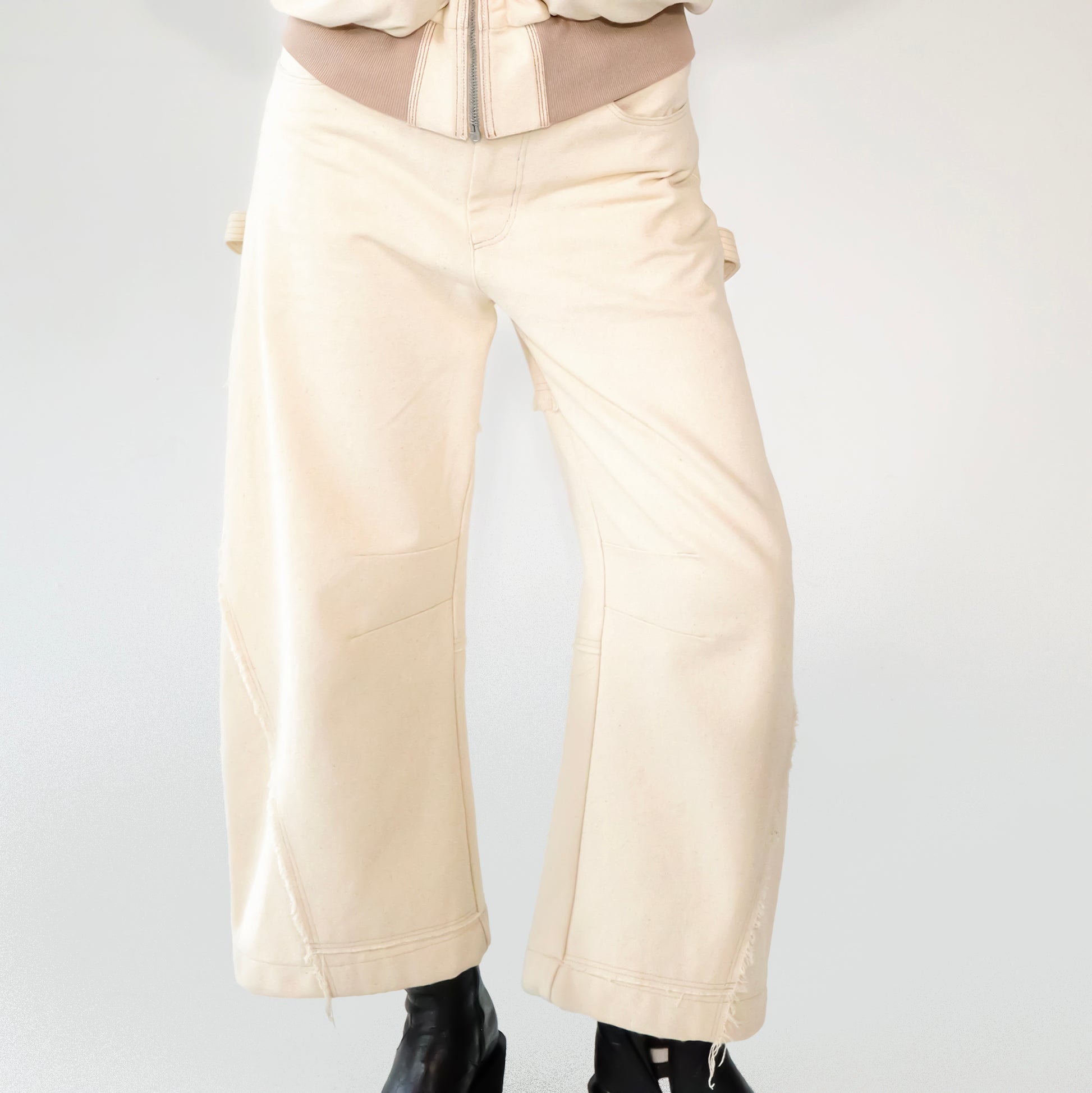 Beige barrel-leg cargo pants with patch detailing worn with a beige bomber jacket on a white background