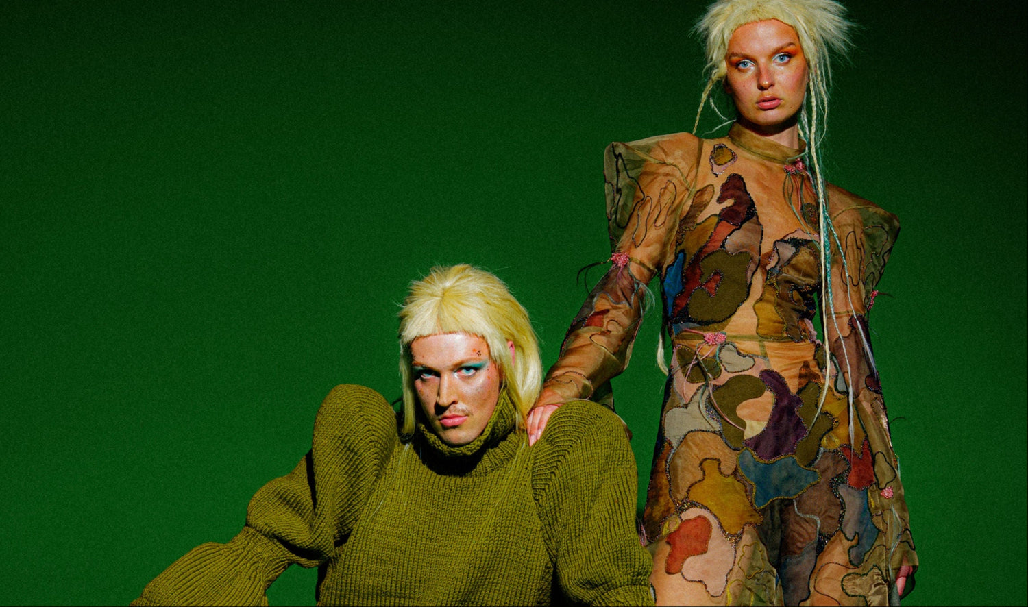 two models in avant garde runway collection pieces. hand embroidered silk organza jumpsuit and hand knit sweater and barrel shaped screen printed and embroidered pants