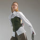 Woman wearing a white shirt with hand embroidered  ant illustrations under a green front lace up corset and khaki wide leg trousers against a gray background