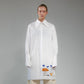 Person wearing a white button up long shirt with hand embroidered designs on a gray background