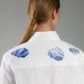 White shirt with blue hand embroidery clouds on the back, worn by a person on a gray background