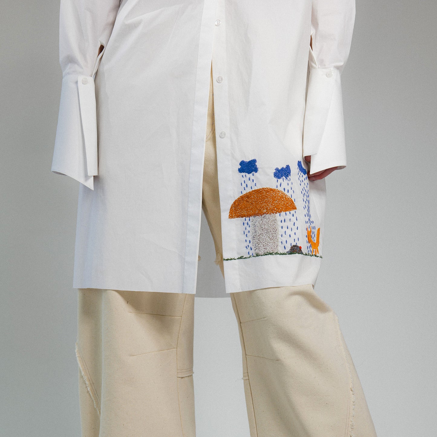 White shirt with colorful hand embroidery on a gray background