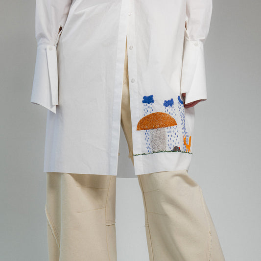 White shirt with colorful hand embroidery on a gray background
