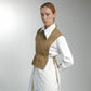 Woman wearing a brown patterned vest over a white shirt on a gray background