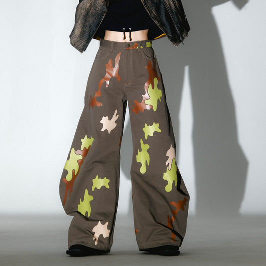 Person wearing camouflage-patterned barrel leg pants with a cropped hoodie, photo on white background with intense shadow