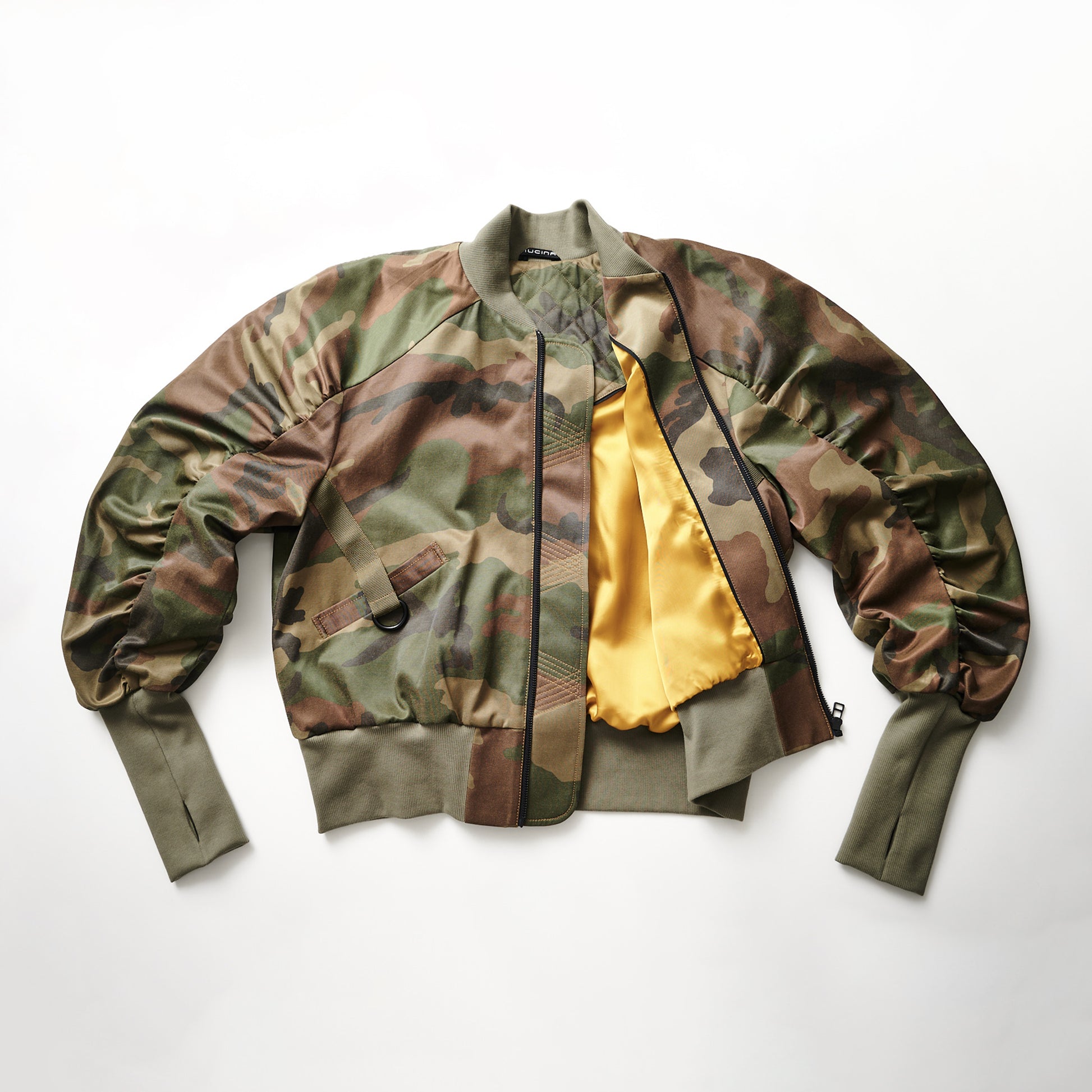 A camouflage bomber jacket laid out flat with the interior lining visible, featuring ribbed cuffs and functional pockets.black streetwear bomber jacket minimalist designer jacket
